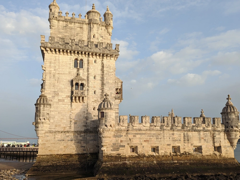 A detailed, low-angle shot of the historic Manueline architecture of the iconic Belém Tower on the banks of the Tagus River in Lisbon.