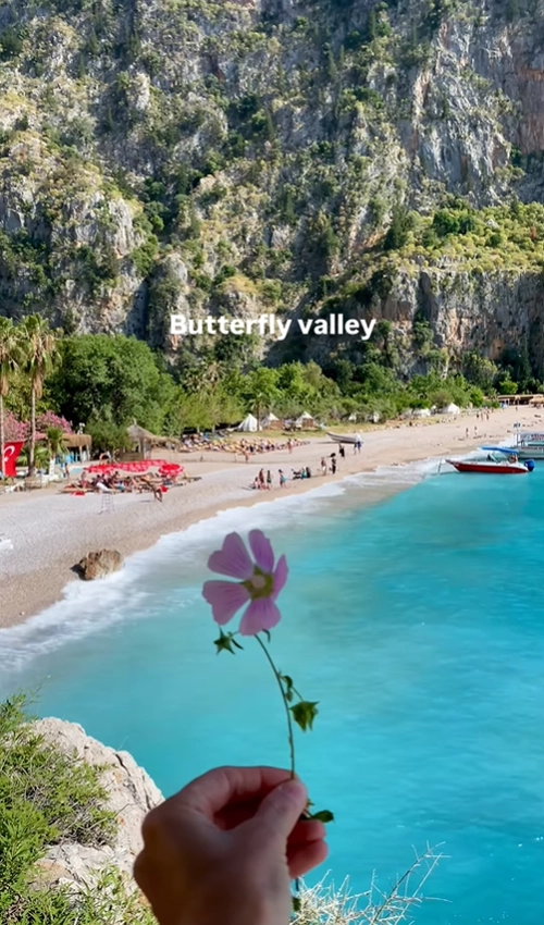 A stunning panoramic view of Butterfly Valley beach and its vibrant turquoise water, framed by dramatic coastal cliffs in Turkey.
