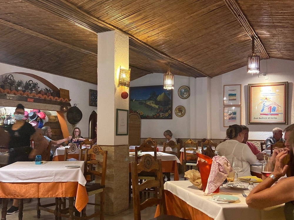 The cozy, traditional interior of La Cabane Restaurant with guests dining in Quarteira, Portugal.