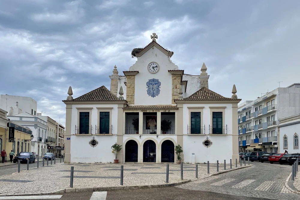 Exterior of Igreja Matriz de Olhão (main church) with its white facade, clock, and azulejos in the main square of Olhao, Portugal.