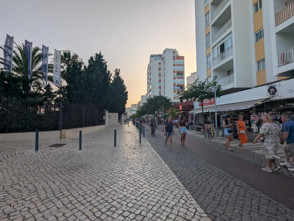 People walking along a lively street in Portimão during a summer evening, highlighting peak nightlife season