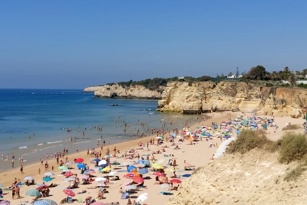 Crowded Praia do Vale do Olival beach with golden cliffs, Armação de Pêra, Algarve