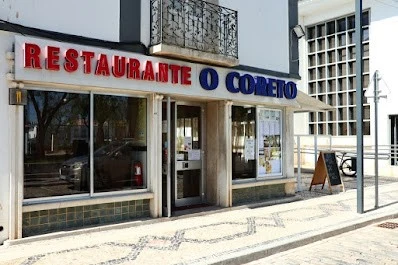 The storefront of Restaurante O Coreto in Tavira, with a red and blue sign above the large windows.