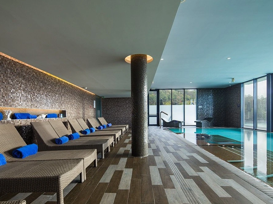 The tranquil indoor pool area at the Sensonal Spa in Monchique, with lounge chairs and b