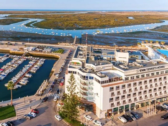 Aerial view of the AP Eva Senses Hotel, showcasing its prime location beside the Faro Marina and the expansive Ria Formosa.