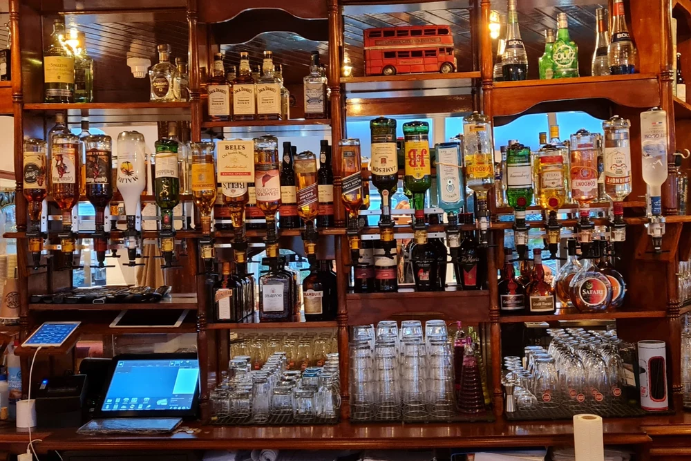 Liquor bottles and glasses behind the bar counter at Waterdog Bar, Armação de Pêra, Algarve