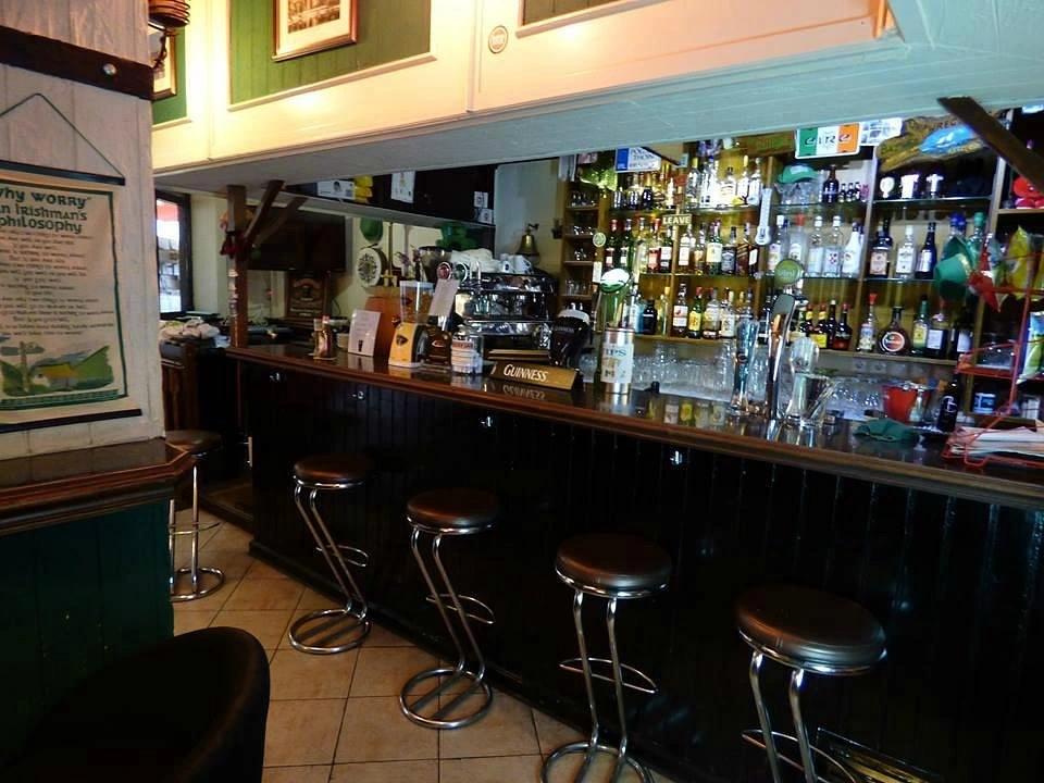 The classic dark wood bar and well-stocked shelves inside Baz & Minnie's Irish Pub in Quarteira.