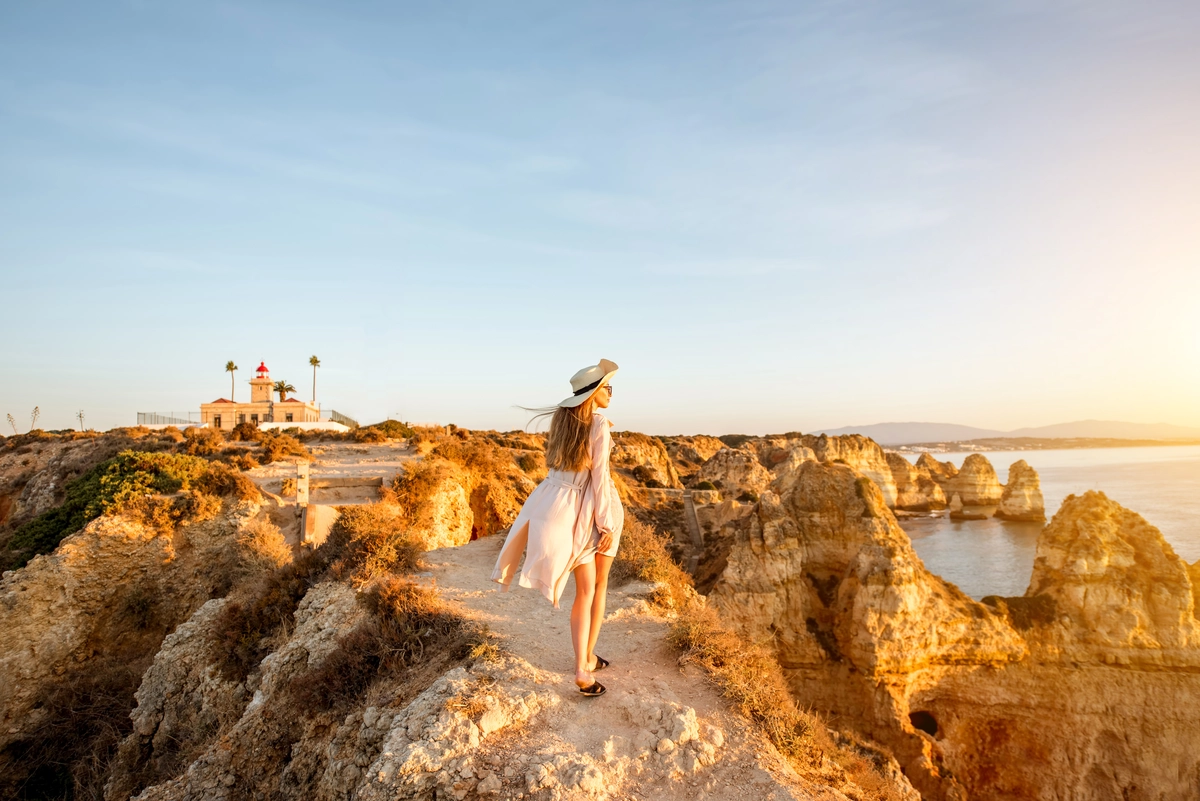 Woman walking on the cliffs in Lagos, Portugal at sunset