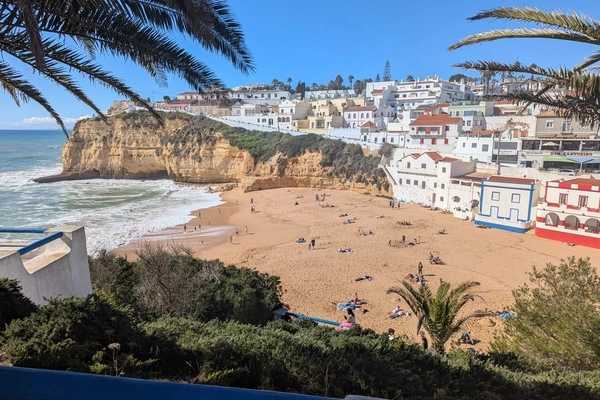 Carvoeiro Beach in Algarve, Portugal, with whitewashed houses on cliffs overlooking the golden sand and turquoise sea.