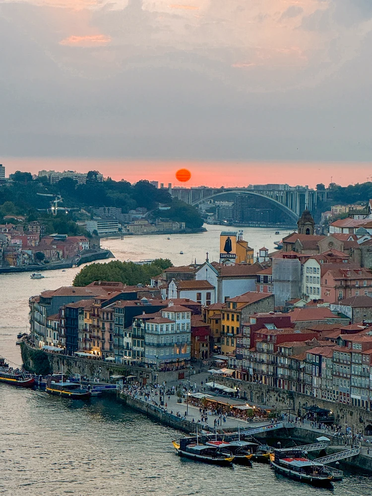 Scenic sunset view over the Douro River and Porto's Ribeira district from the Dom Luís I Bridge.