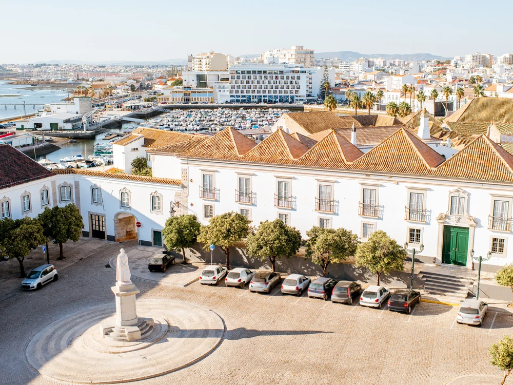 Sunny, elevated view of Largo da Sé, the historic main square in Old Town Faro, with the city and marina in the background.