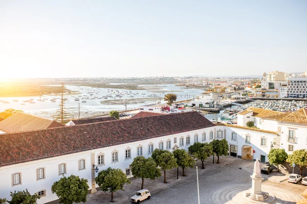 Panoramic sunset view over Faro's Old Town, the bustling marina, and the expansive Ria Formosa estuary.
