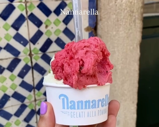 A cup of fresh pink raspberry gelato against a traditional Portuguese tiled wall from Gelateria Nannarella in Lisbon.