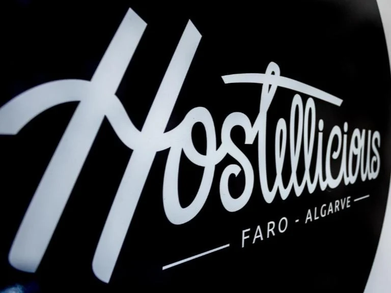 The stylish black and white logo for the popular Hostellicious hostel, located in Faro, Algarve.