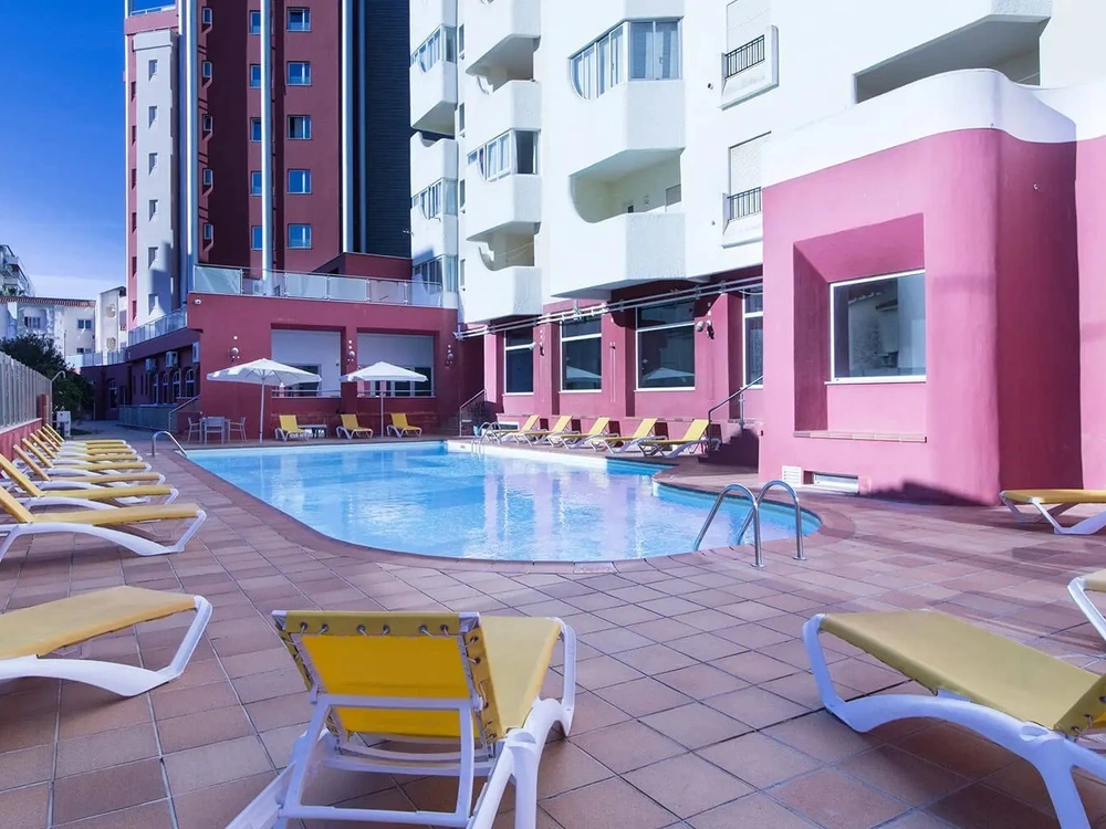 The outdoor swimming pool and sun loungers on the terrace of Hotel Quarteira Sol in Quarteira.