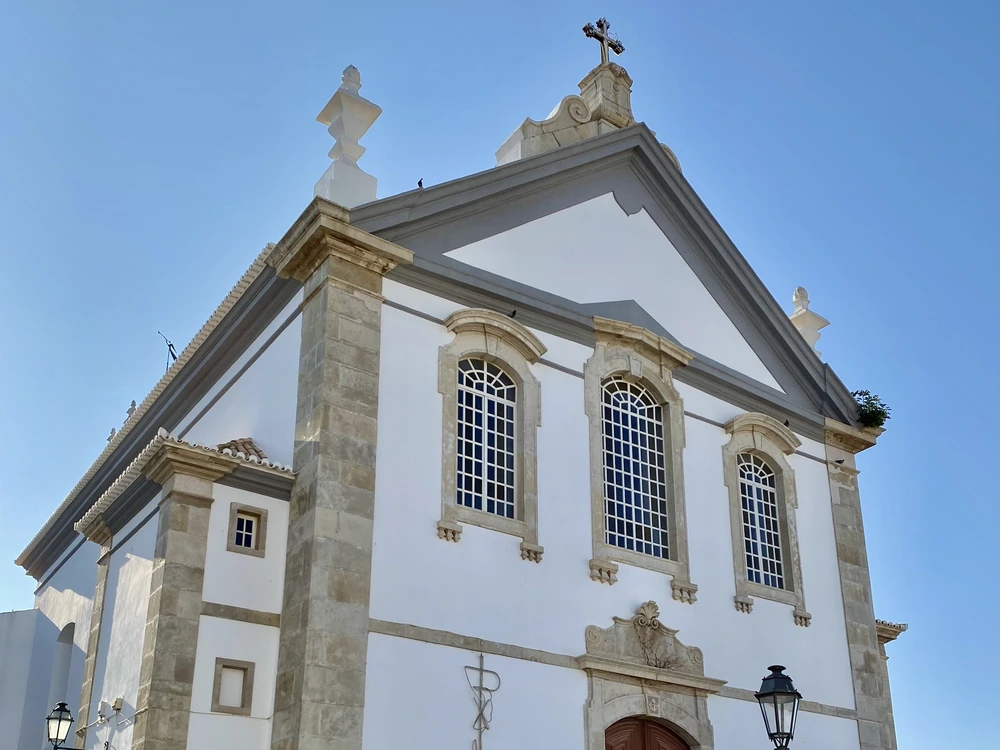 The stunning neoclassical facade of the Igreja Matriz de Albufeira, the main parish church in Albufeira, showcasing its white walls and stone details.