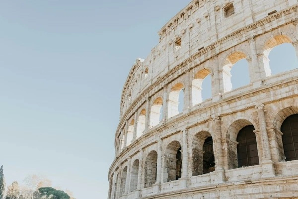 Close-up view of the ancient Roman Colosseum in Rome, Italy, under a clear blue sky.