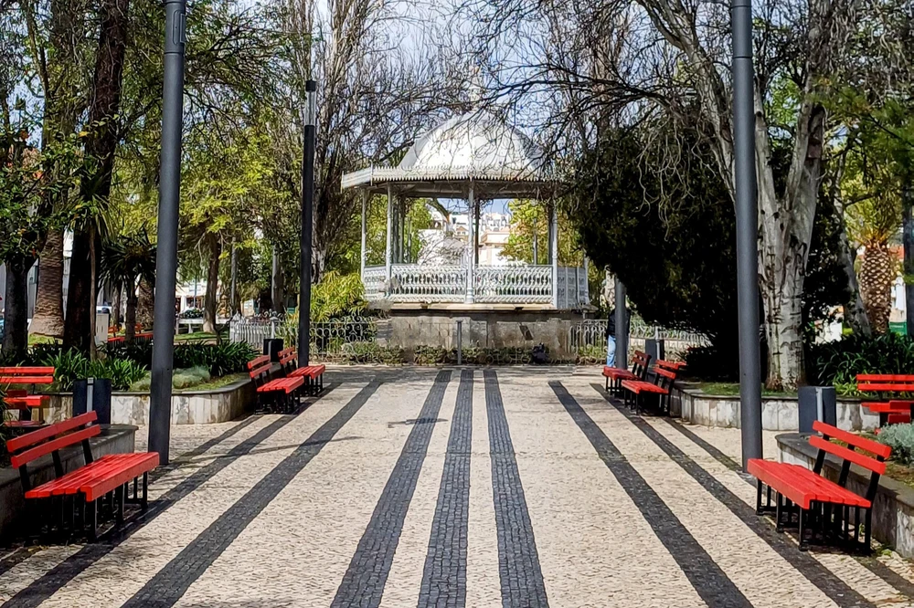 The central walkway and ornate white bandstand (coreto) in the green Jardim do Coreto park in Tavira.