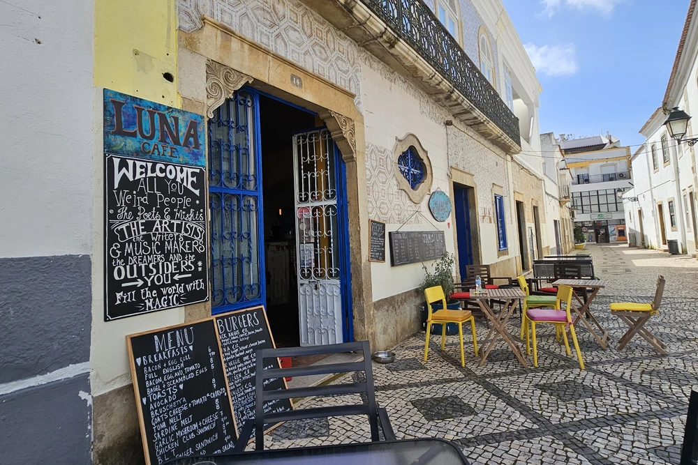 Exterior of Luna Art Cafe with vibrant outdoor seating and traditional Portuguese architecture in Olhao, Portugal.