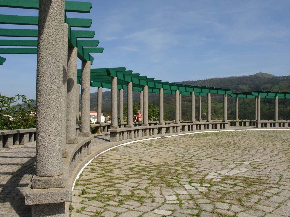 The stone plaza and green pergola at the Miradouro de Monchique, a scenic lookout point over the town and mountains.