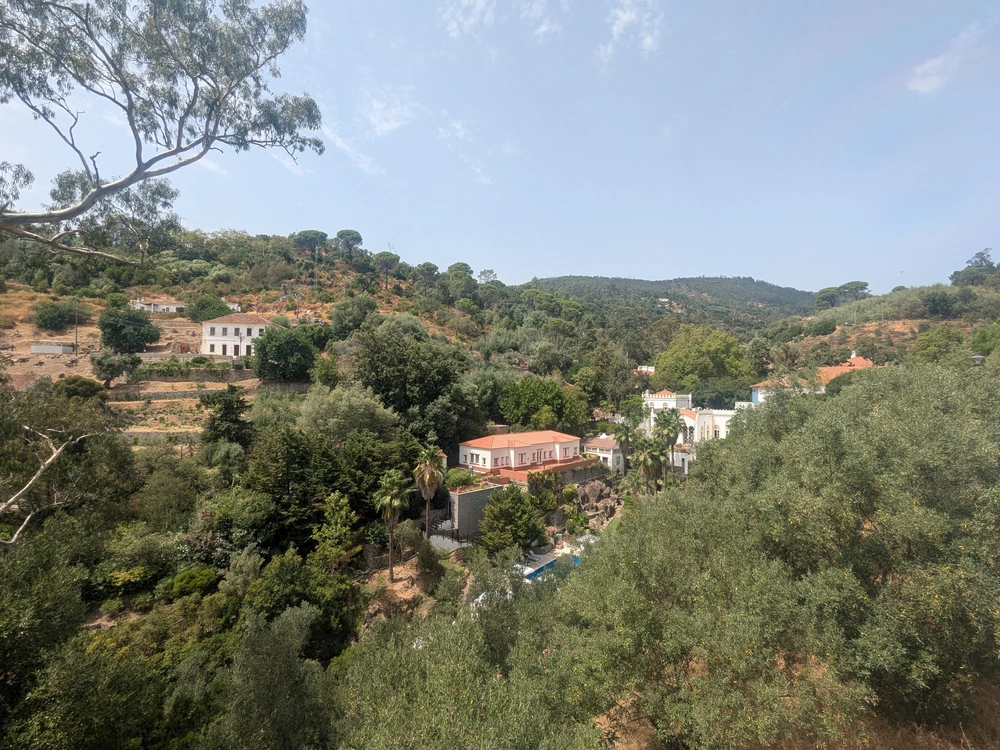 A scenic mountain view of the Caldas de Monchique area, with villas and trees dotting the verdant landscape.