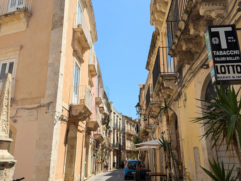Narrow street in Ortigia’s La Giudecca district with balconies and pastel buildings – Ortigia city guide