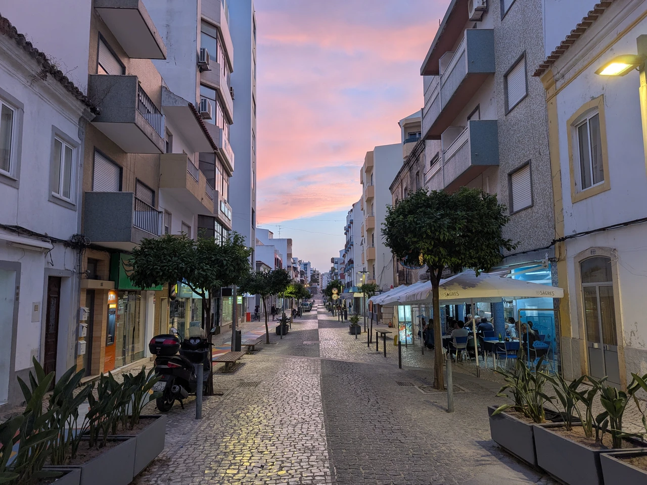 Rua Direita in Portimão at sunset with cobblestone path, outdoor café seating, and pastel sky
