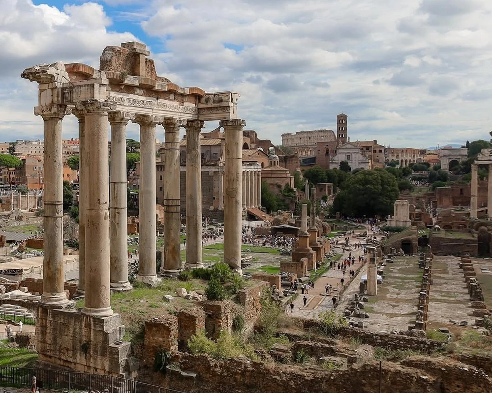 The majestic ruins of the Roman Forum, with the columns of the Temple of Saturn in the foreground. This unique perspective highlights finding non-touristy viewpoints of famous historical sites in Rome.