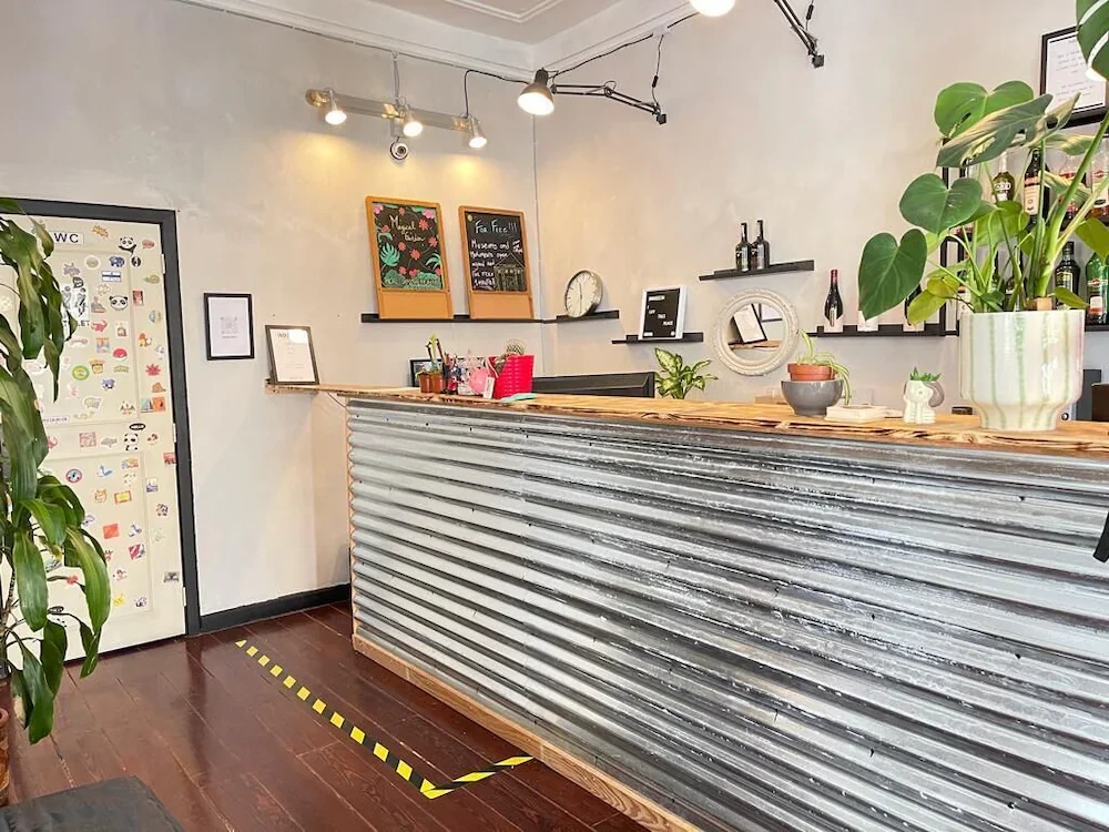 The trendy and welcoming reception area of the Rossio Hostel in Lisbon, with a corrugated metal desk and eclectic, plant-filled decor.