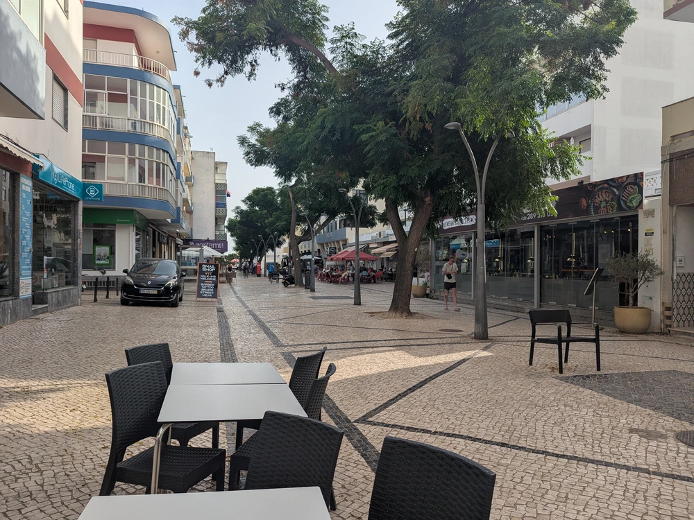 Outdoor cafe seating on the traditional cobblestone walking street of Rua Vasco da Gama in Quarteira.