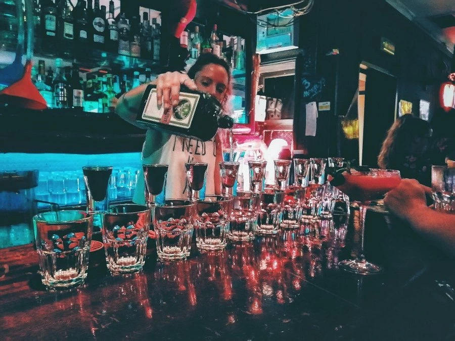 Three Monkeys Bartender pouring cheap shots