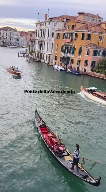 View from the Ponte dell’Accademia in Venice, showing a gondola navigating the Grand Canal with historic buildings alongside it.