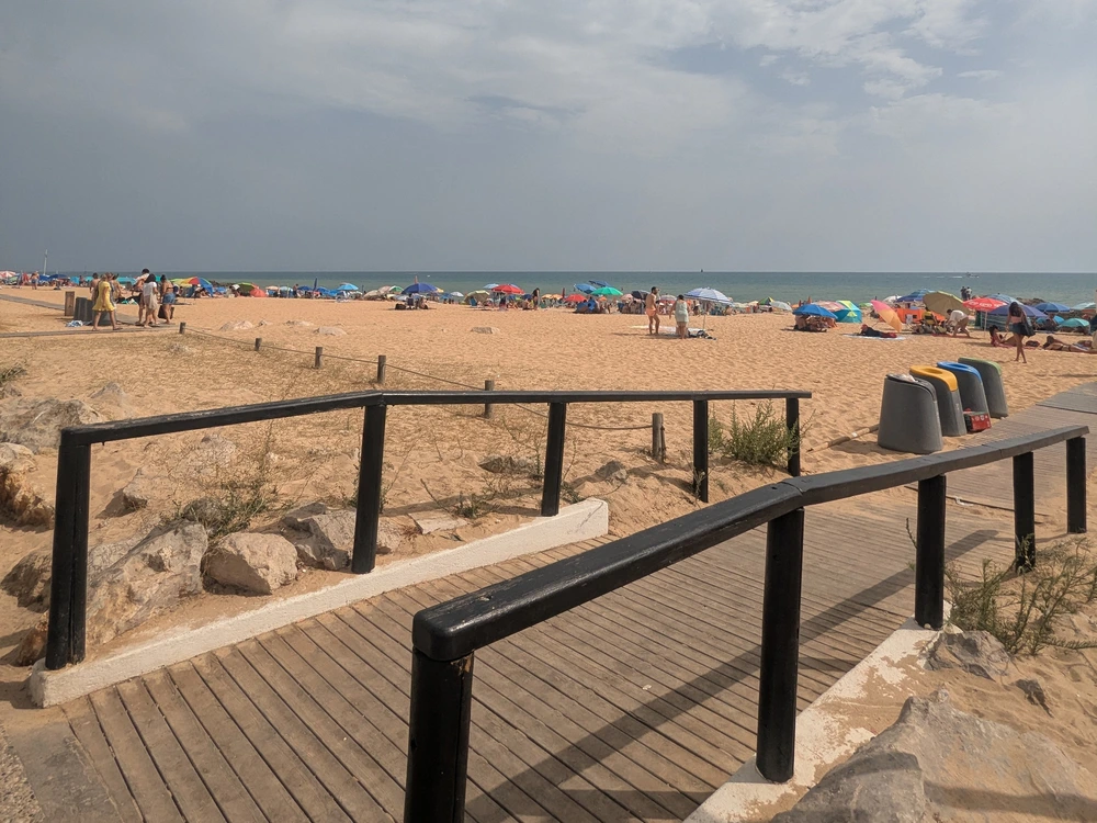 The boardwalk leading onto the wide, sandy beach of Quarteira, a lively neighboring town perfect for a day trip from Vilamoura.