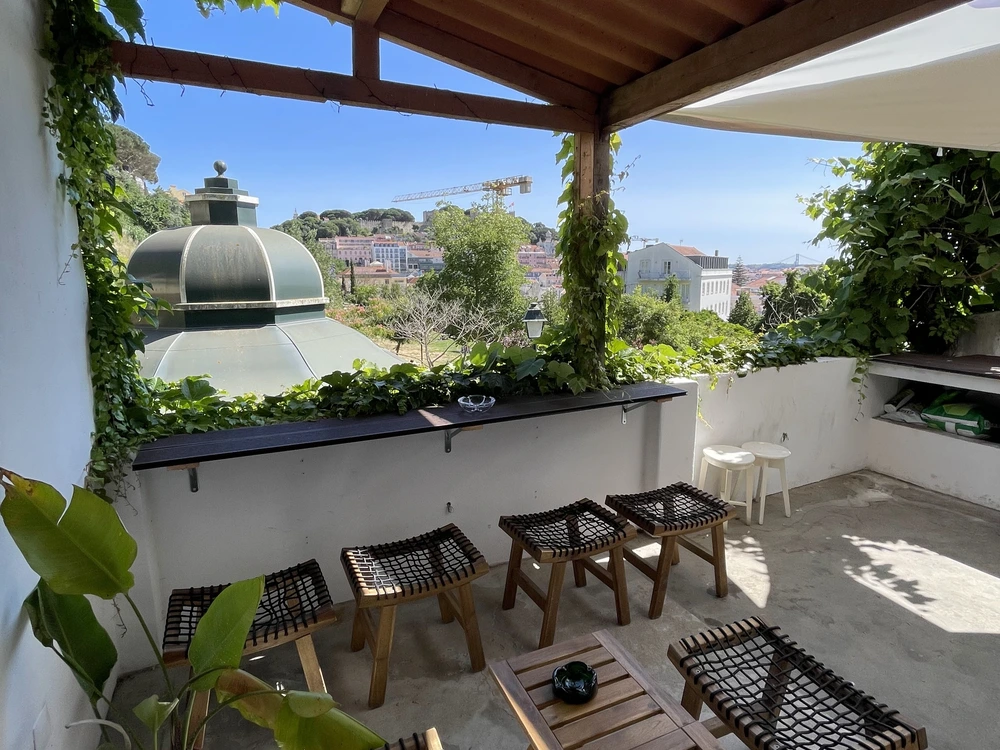 The cozy and plant-covered outdoor terrace at VIS | X Devil's Pie Bar in Lisbon, offering a charming view over the city's rooftops.
