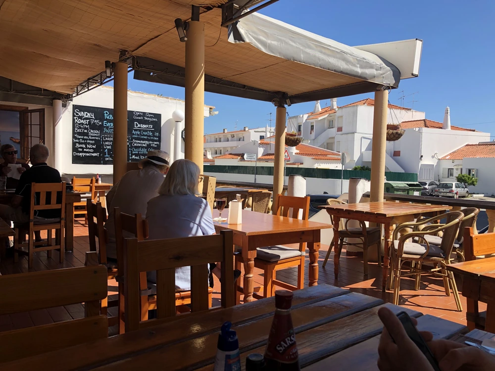 Diners enjoying a sunny afternoon on the outdoor terrace of the Wander Inn, a restaurant known for English comfort food in Albufeira.