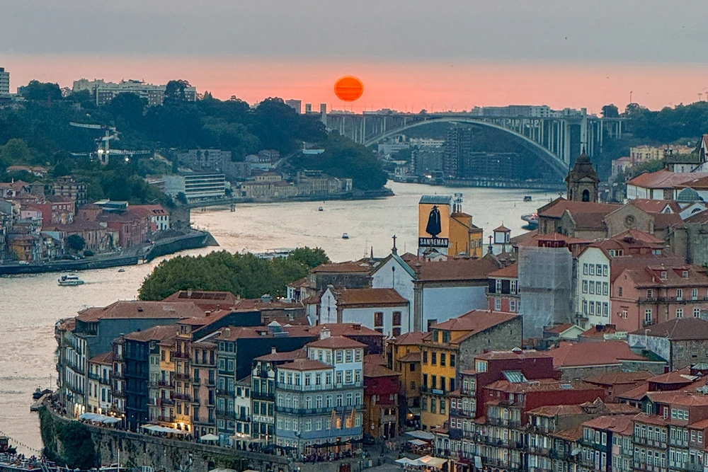 Scenic sunset view over the Douro River and Porto's Ribeira district from the Dom Luís I Bridge.