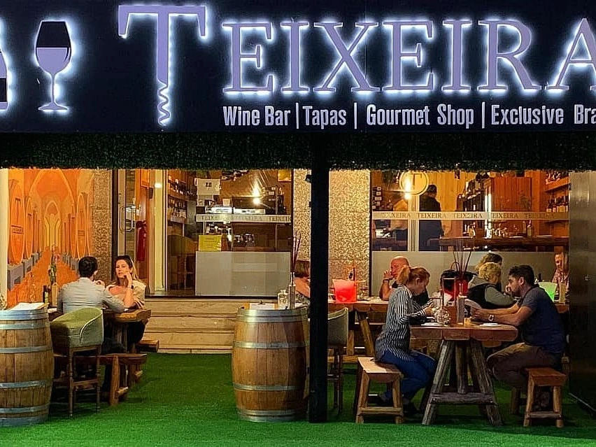 The lively outdoor seating area at night in front of the Wine Cellar Teixeira bar in Quarteira, Portugal.
