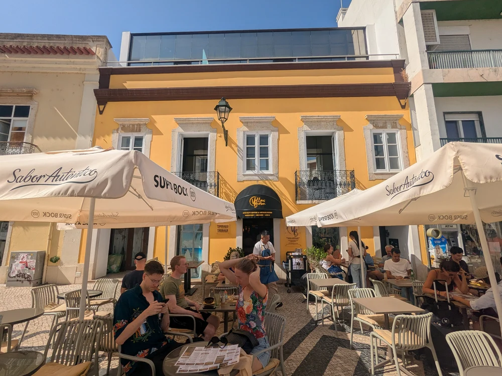 Patrons relaxing on the sunny outdoor terrace of Yellow Bourbon Coffee Brunch in the cobblestone streets of Old Town Faro.